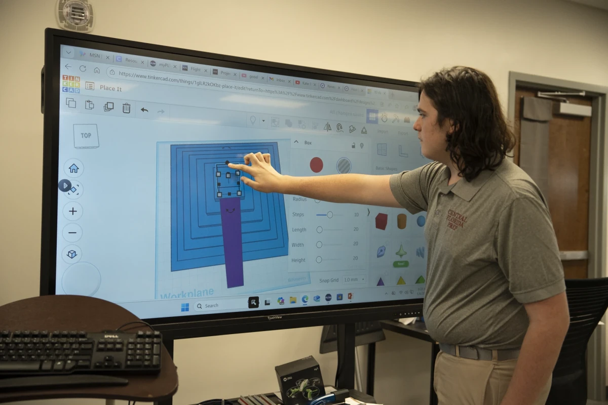 A Central Florida Prep teacher points to a circuit design on a large touchscreen in the STEM lab