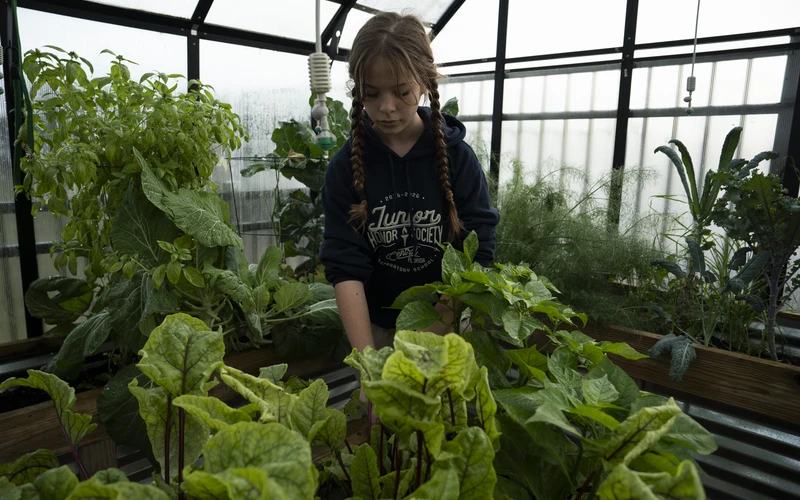 A student tending plants in the Central Florida Prep greenhouse